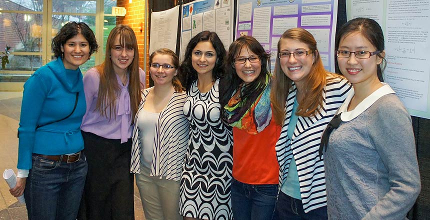 Seven women from the Math Department at a poster session.