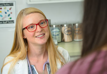 在护理诊所里，一名护理专业的学生微笑着与病人聊天