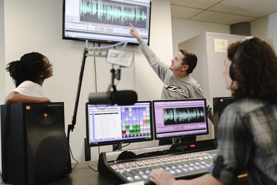 两名学生播音员在播出的生产中在UA WZIP无线电工作室工作。
