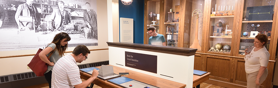 博物馆的游客聚集在一个交互式显示。两个是与显示和交互两人正在看从一段短距离的路
